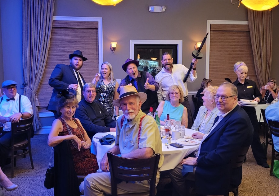 Riddlesbrood actor in 1940s attire posing with senior guests during nostalgic senior entertainment event in NJ